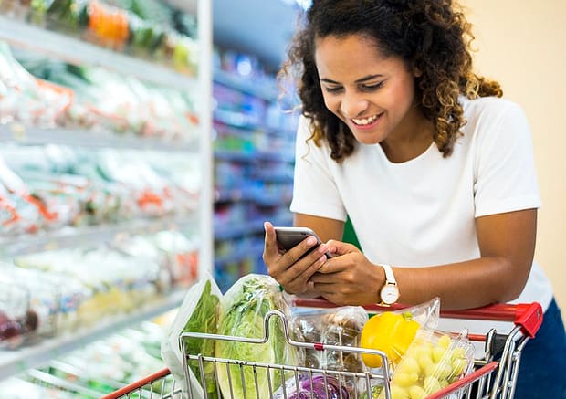 woman holding a cellphone while grocery shopping